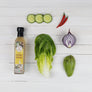 Organic Coconut Vinegar 500ml with fresh salad ingredients including avocado lettuce and cucumber on white wooden background